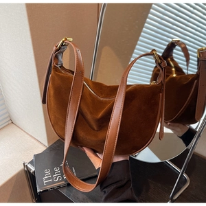 Macro shot of dark brown suede hobo bag with gold hardware and leather shoulder strap