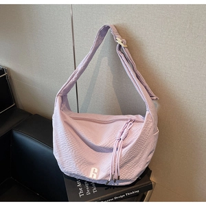 Detail of lavender textured woven fabric and logo on large capacity crescent shoulder bag