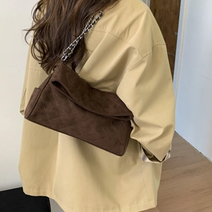 Detailed view of the dark brown suede shoulder bag with quilted diamond pattern and chain strap