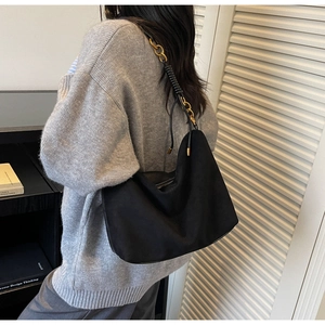 Detail of minimalist black suede crescent bag with gold chain strap and matte finish