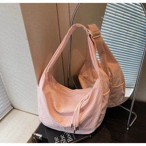 Detail of pink textured fabric tote with side pocket and decorative tassel rope strap