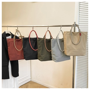 Detail view of colorful woven rope handles and multi-color tote bags on a metal rack