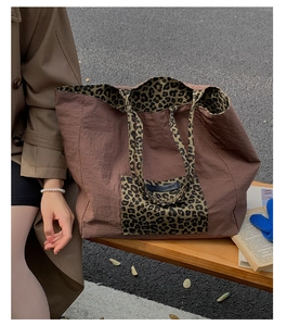 Close-up of leopard print tote bag with Own The Moment text on a wooden bench