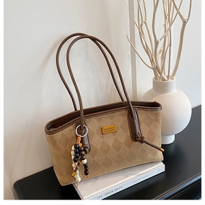 Detailed view of brown suede tote with diamond quilting and wooden bead tassel ornament