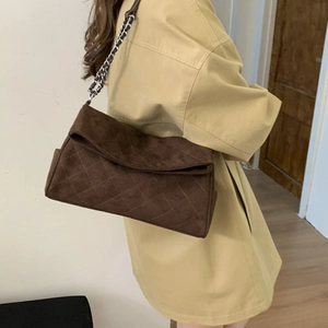 Detail of dark brown suede shoulder bag with diamond quilting and silver chain strap