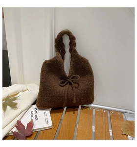Detailed close-up of dark coffee knit tote bag with bow knot and autumn props decor