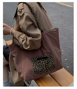 Detail of leopard print tote bag with woven label on soft brown fabric in outdoor setting