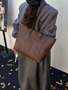 Detail of a large dark brown faux leather tote bag styled with a wool coat for autumn