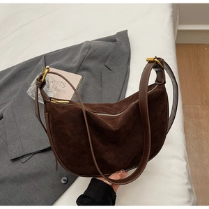 Detail of dark brown suede crescent bag with smooth leather strap and gold hardware