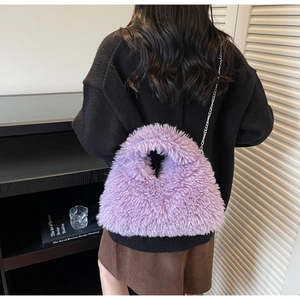 Detail der lila Plüsch-Tasche mit Silberkette, präsentiert von einem Model