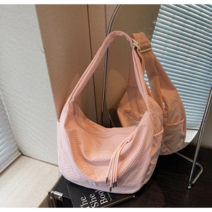 Detailed close-up of pink waffle texture crossbody bag with tassel and zip closure