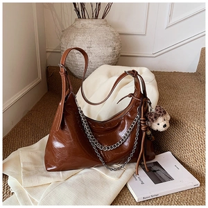 Detail of vintage brown patent leather handbag with silver chain and leopard bow bear charm