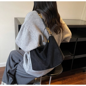 Detailed back view of a black suede hobo bag with a gold chain strap on a model