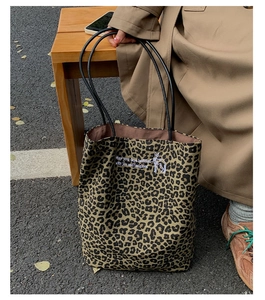 Detail of leopard print tote bag featuring embroidered text and slender black straps