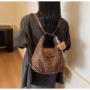 Detail of leopard print tote bag with brown leather flap and cute bear pendant