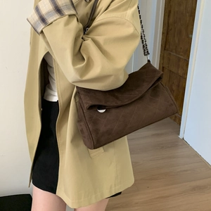 Detail of dark brown suede shoulder bag featuring quilted rhombic texture and chain strap