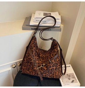 Detail of leopard print bucket bag featuring brown leather straps and gold buckle accents