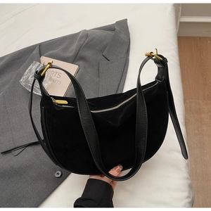 Detail of black suede crescent bag with leather strap and golden zipper closure