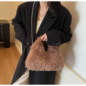 Detail der flauschigen braunen Lammwoll-Handtasche mit Silberkette am Modell im Anzug