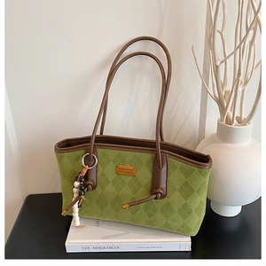 Detail of green suede tote bag featuring diamond quilt pattern and brown leather straps