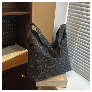Detail of leopard print hobo tote bag featuring wide shoulder strap on vintage books