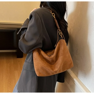 Detail of a brown suede hobo bag with unique woven shoulder strap and metal chain