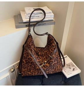 Detail of leopard print tote bag with brown leather straps and gold buckle accents