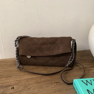 Detail of dark brown suede crossbody bag featuring diamond quilted stitching and chain strap