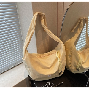 Close-up of light yellow crescent bag featuring fine grid texture and logo detail