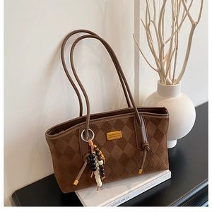 Macro detail of brown faux suede tote bag with embossed diamond pattern and wooden beads