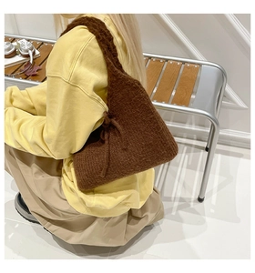 Detail view of a brown knitted tote bag with textured lambskin-like fabric on a shoulder
