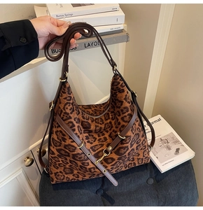 Detail of leopard print hobo bag with gold hardware and brown leather strap on a blue stool
