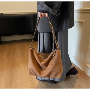Detail of vintage brown suede shoulder bag with leather and gold chain strap handle