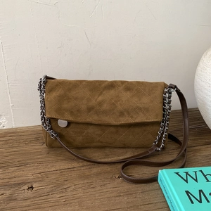 Detail of brown suede crossbody bag with quilted stitching and silver chain strap