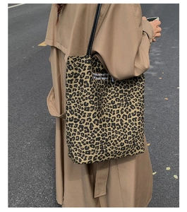 Detail view of leopard print tote bag with black straps and vintage style on a model