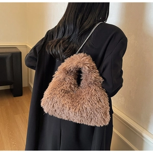 Detailaufnahme der braunen Lammfell-Tasche mit Silberkette auf schwarzem Blazer