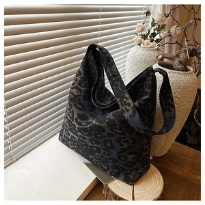 Close-up of leopard print tote bag on a sunlit wooden table with floral accents