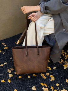 Close-up of deep brown soft leather tote bag with vintage matte texture and long handle