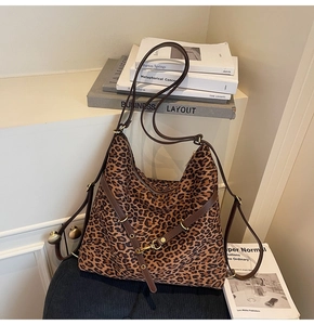 Detail of leopard print tote bag with brown leather straps and gold buckle closure