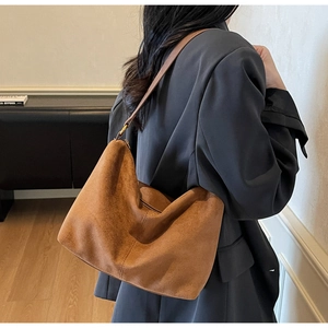 Detail of caramel suede tote bag featuring slim straps and gold metal buckle on shoulder
