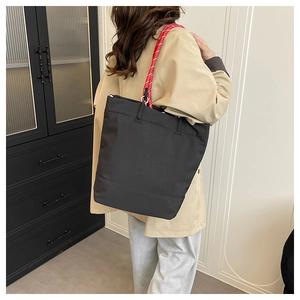 Detail of black tote bag featuring distinctive pink and gold braided rope handles