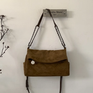 Detail of brown suede crossbody bag with diamond quilting and silver chain strap