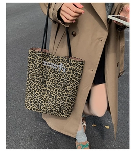 Detail of leopard print tote bag with black straps and inspirational text in a street setting