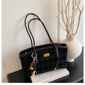 Detail of black suede tote bag with checkered embossing and colorful beaded tassel