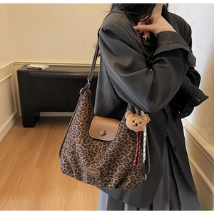 Close-up of leopard print tote bag with brown leather flap and cute bear pendant