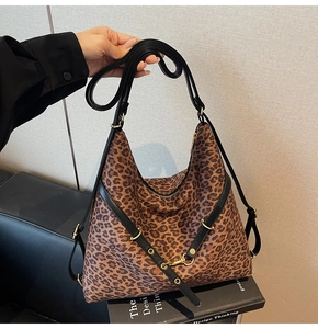 Macro shot of large leopard print bucket bag with black leather strap and gold metal rivets
