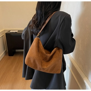 Close-up of a caramel brown suede hobo bag styled as a vintage minimalist shoulder bag