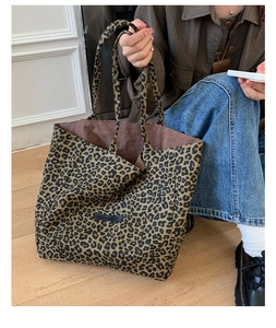 Detail of leopard print tote bag with brown lining and Own The Moment logo label