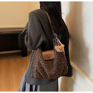 Detail of leopard print tote bag with brown bear charm and magnetic leather flap closure