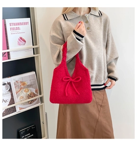 Detail of red knit handbag with bow accent shown on model with cozy autumnal styling